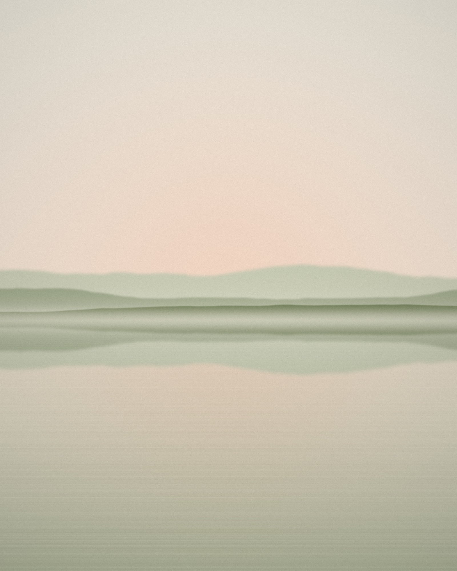 A perfectly still lake mirroring a hazy shoreline